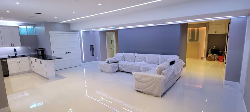 Interior photo of an open living room and kitchen with white floors in Hicksville, NY