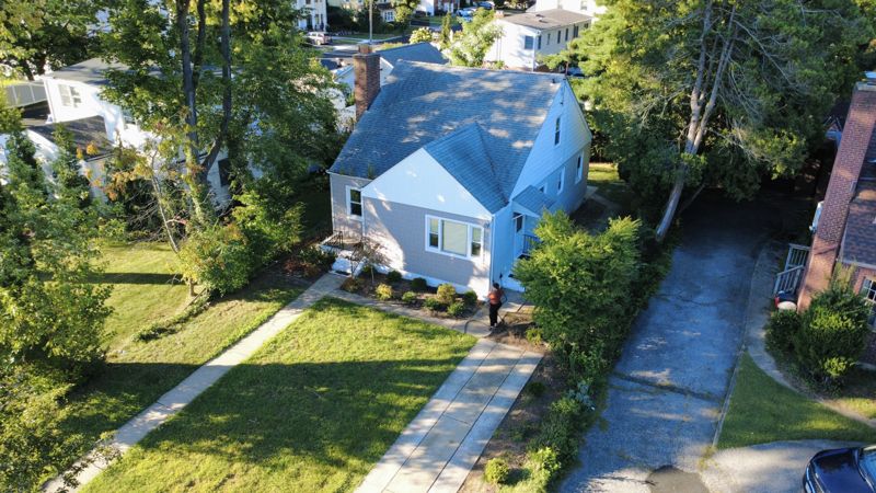 Drone photo of a blue cape-style home, front lawn and driveway in West Hempstead, NY