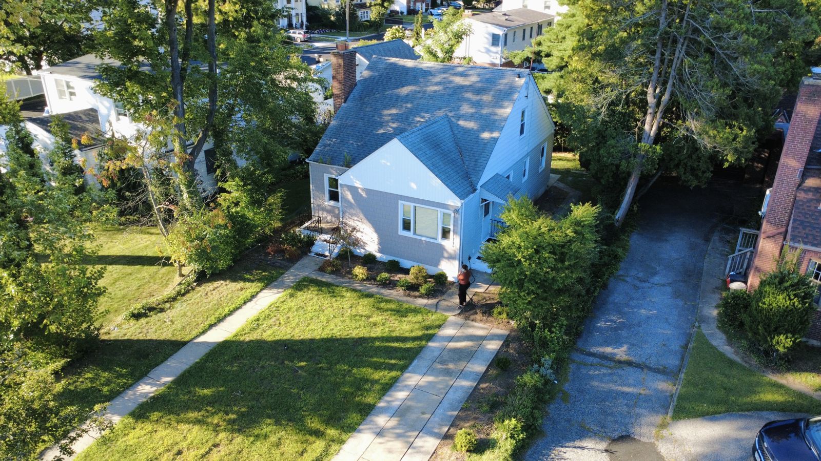 Low-angle drone photo of a blue cape-style home in West Hempstead, NY